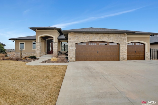 prairie-style home featuring stucco siding, stone siding, driveway, and an attached garage