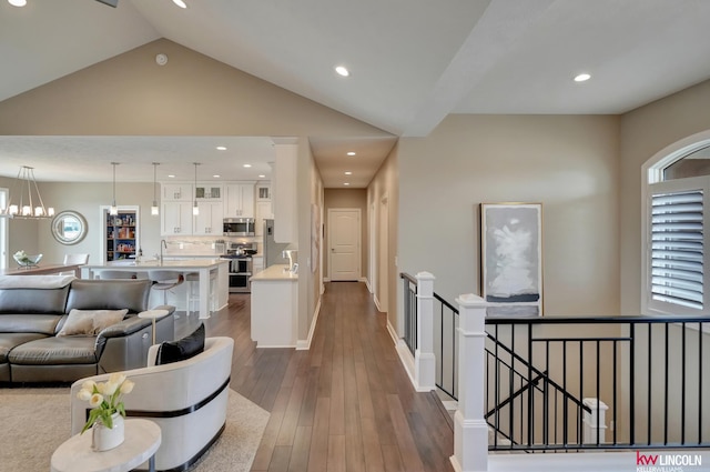 interior space with dark wood-type flooring, recessed lighting, baseboards, a chandelier, and vaulted ceiling