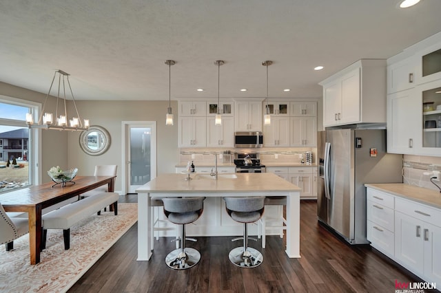 kitchen featuring backsplash, dark wood finished floors, white cabinetry, stainless steel appliances, and light countertops