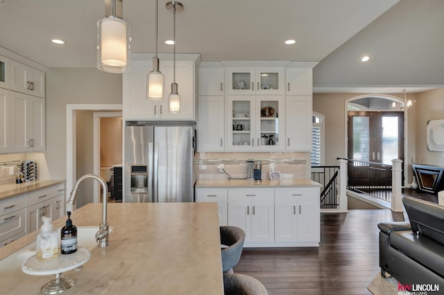 kitchen featuring decorative backsplash, white cabinets, light countertops, and stainless steel refrigerator with ice dispenser