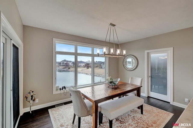 dining room featuring dark wood-type flooring, a notable chandelier, visible vents, and baseboards