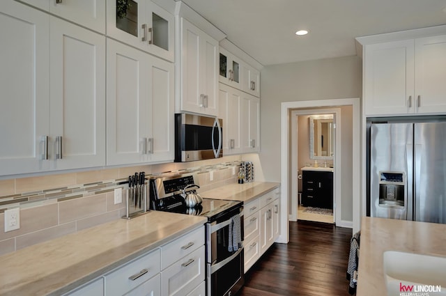 kitchen with backsplash, white cabinets, appliances with stainless steel finishes, and glass insert cabinets