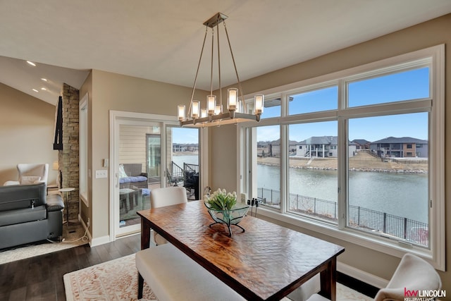 dining area featuring baseboards, a water view, lofted ceiling, dark wood-style floors, and a notable chandelier