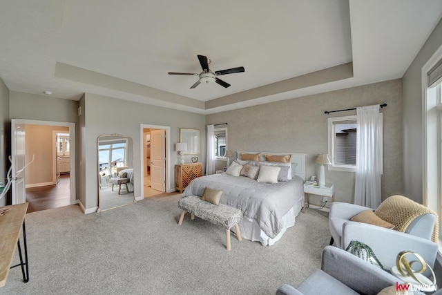 bedroom with a tray ceiling, baseboards, and carpet flooring