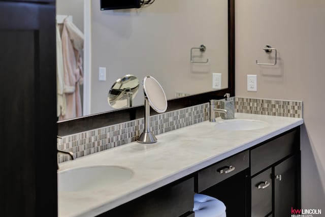 full bath featuring a sink, tasteful backsplash, and double vanity