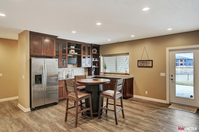 kitchen featuring open shelves, light wood finished floors, stainless steel fridge with ice dispenser, and backsplash