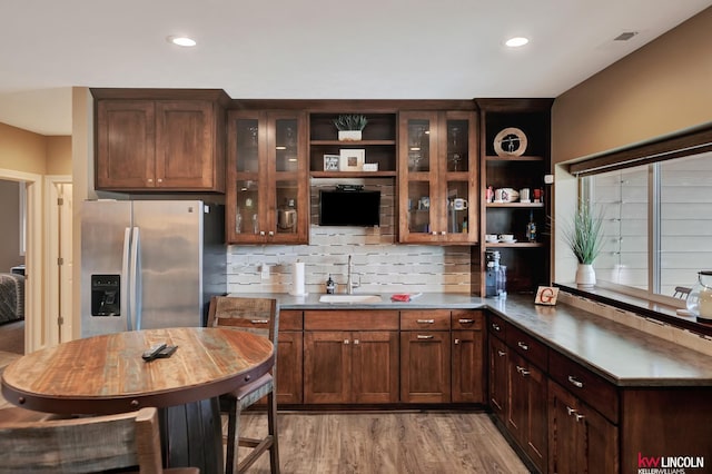 kitchen with tasteful backsplash, a sink, light wood-type flooring, stainless steel refrigerator with ice dispenser, and open shelves