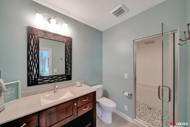 full bathroom with vanity, a shower stall, toilet, and visible vents