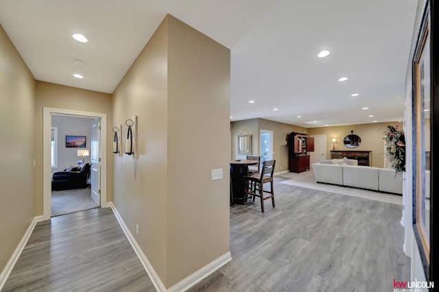 hallway featuring recessed lighting, baseboards, and light wood finished floors