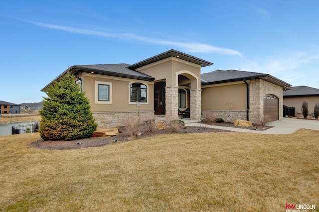 prairie-style house with a front lawn, concrete driveway, stucco siding, stone siding, and an attached garage