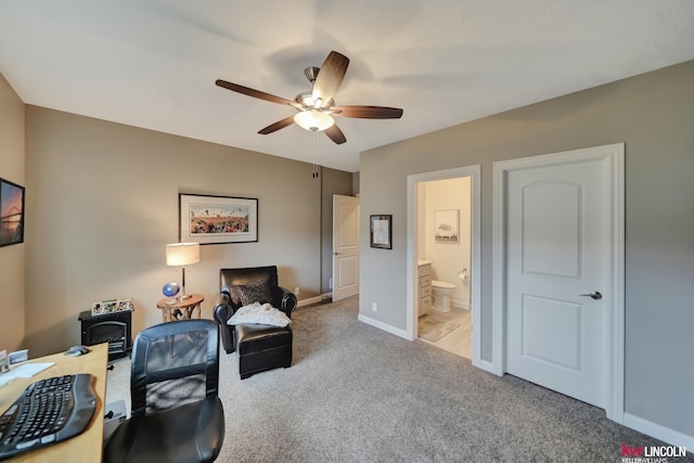 office area featuring baseboards, a wood stove, a ceiling fan, and carpet floors