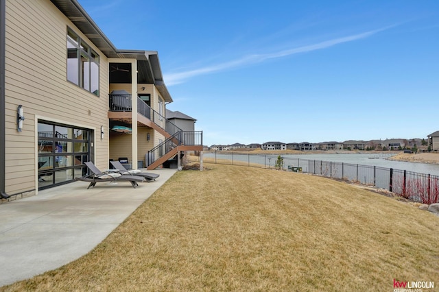 view of yard with a patio area, a water view, stairway, and fence