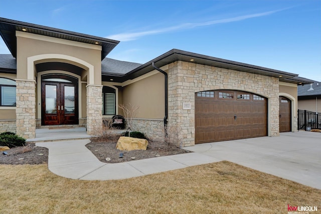 view of front of property with stone siding, french doors, concrete driveway, and a garage