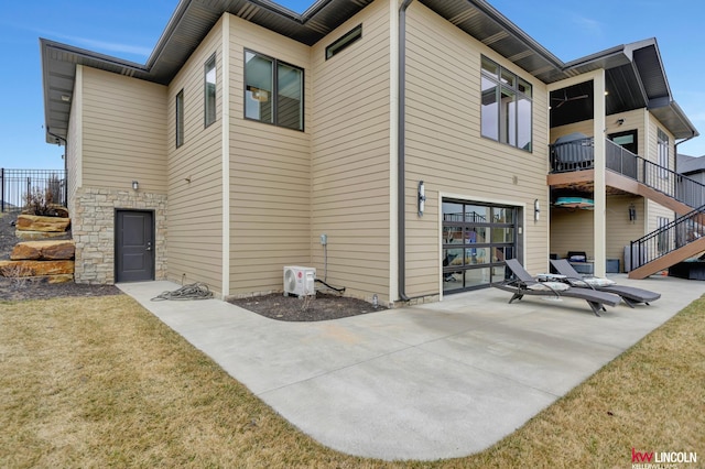 rear view of property with a yard, a patio area, stone siding, and an attached garage