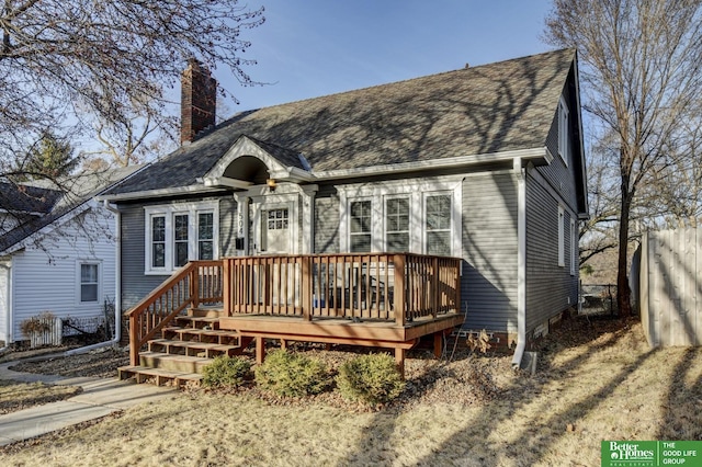 view of front of home featuring a deck, roof with shingles, and a chimney