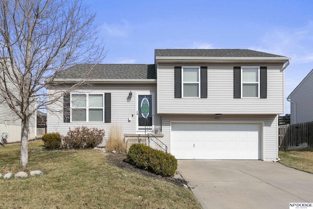 tri-level home featuring driveway, an attached garage, a front lawn, and fence