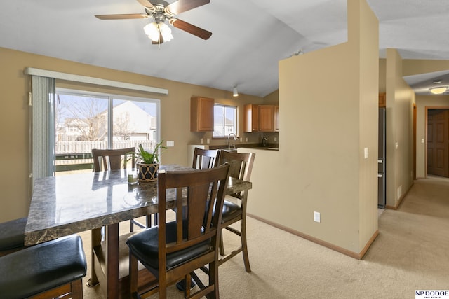 dining room featuring light colored carpet, baseboards, lofted ceiling, and ceiling fan