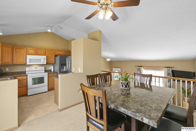 kitchen featuring white appliances, a breakfast bar area, vaulted ceiling, dark countertops, and light colored carpet