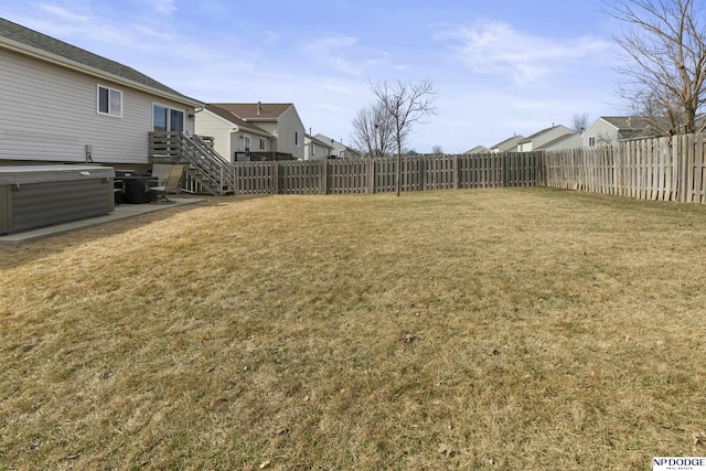 view of yard featuring a residential view, a fenced backyard, and a hot tub