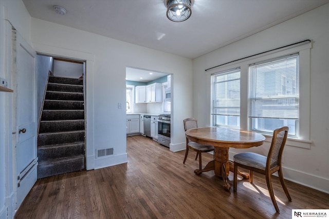 dining area with visible vents, baseboards, wood finished floors, and stairs