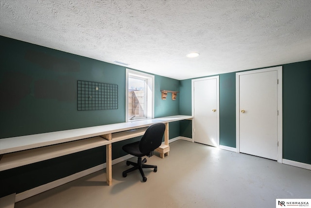 office featuring visible vents, a textured ceiling, concrete flooring, and baseboards