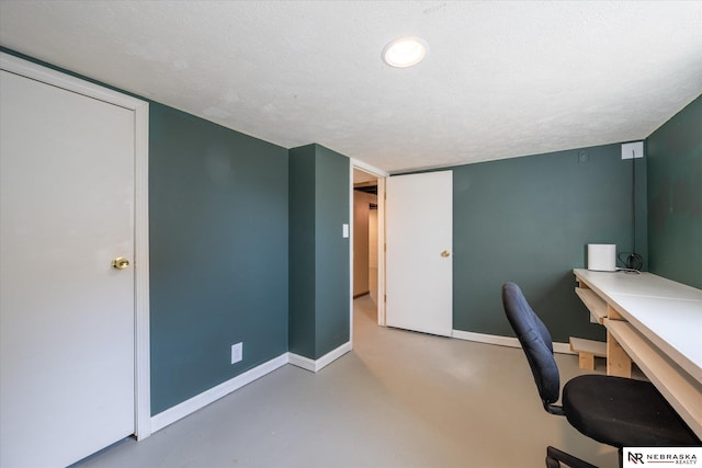 office space with finished concrete flooring, baseboards, and a textured ceiling