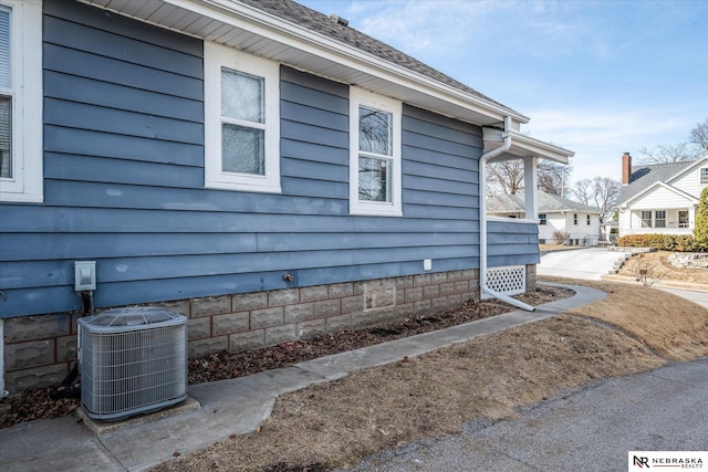 view of home's exterior featuring cooling unit and roof with shingles