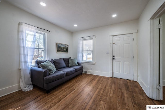 living room featuring dark wood-type flooring, plenty of natural light, and baseboards