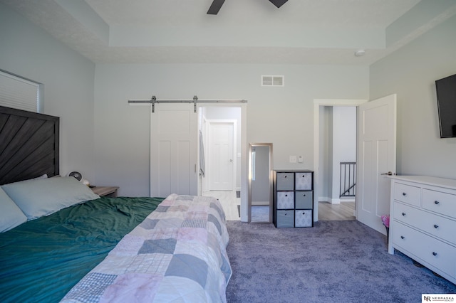 carpeted bedroom featuring visible vents, a ceiling fan, and a barn door