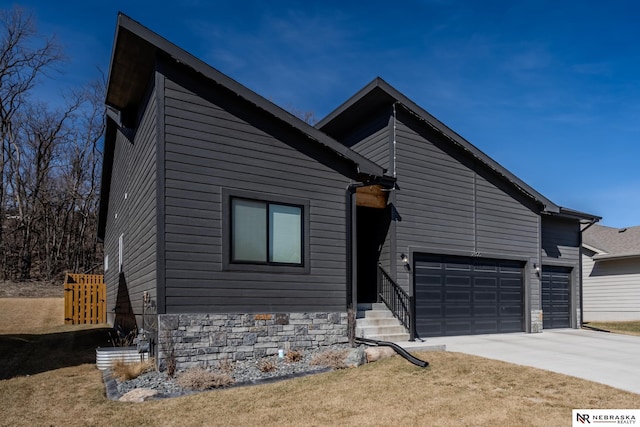 view of front of house with concrete driveway, an attached garage, and stone siding