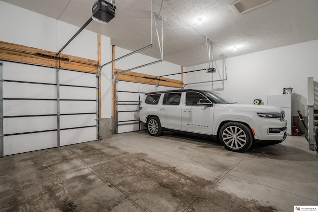 garage with a garage door opener and freestanding refrigerator