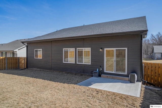 rear view of property featuring a patio area, roof with shingles, and fence