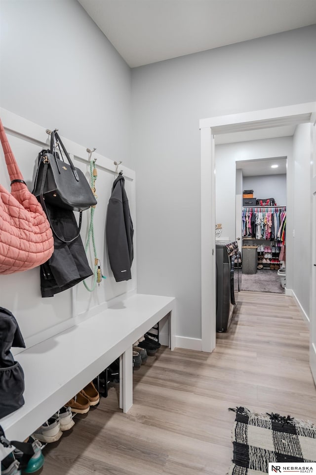 mudroom featuring baseboards, light wood finished floors, and washer and clothes dryer