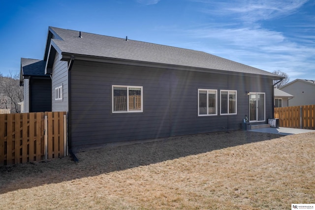 back of house featuring fence and roof with shingles