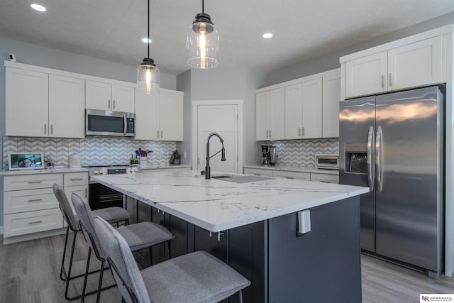 kitchen featuring white cabinetry, decorative light fixtures, light stone counters, and stainless steel appliances