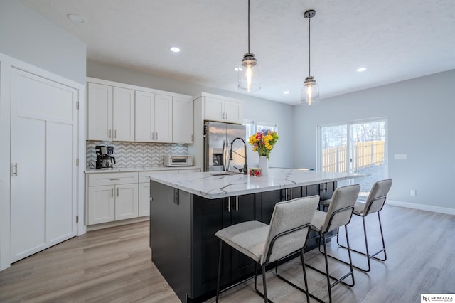 kitchen featuring light wood-style floors, tasteful backsplash, white cabinets, and stainless steel fridge with ice dispenser