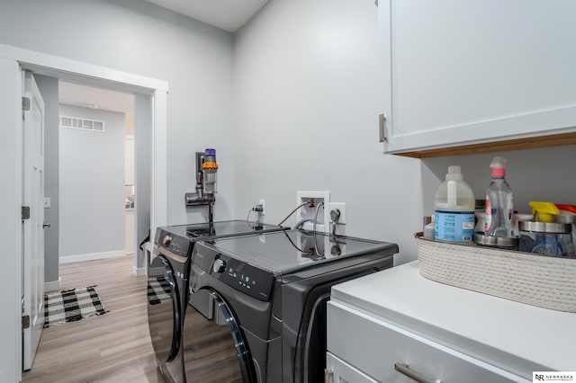 washroom featuring visible vents, cabinet space, washing machine and dryer, and light wood-style flooring