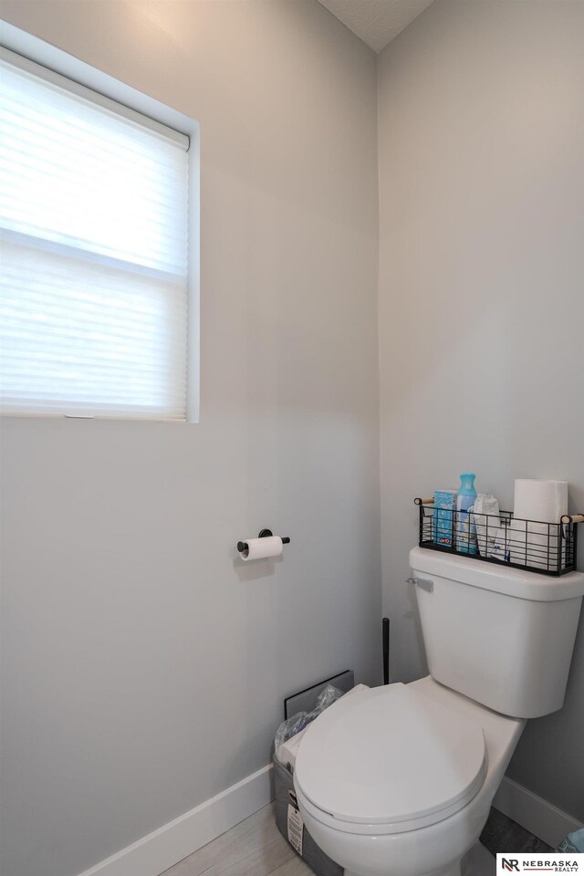 bathroom with toilet, wood finished floors, and baseboards