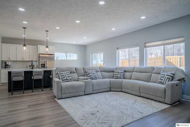 living area with recessed lighting, a textured ceiling, and light wood-type flooring