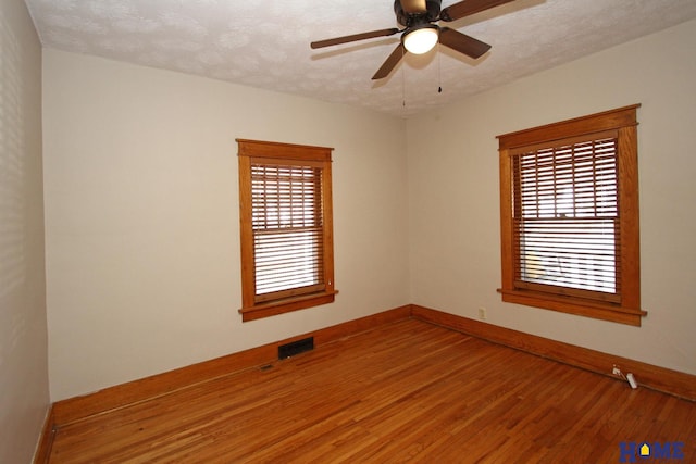 empty room with visible vents, baseboards, a textured ceiling, and wood finished floors