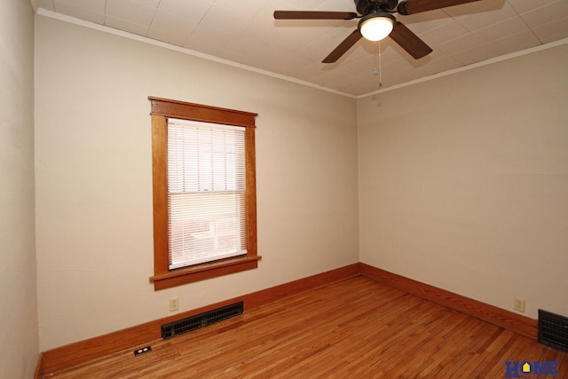 spare room featuring visible vents, wood finished floors, baseboards, and ornamental molding