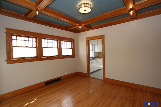 unfurnished room with visible vents, light wood-style flooring, coffered ceiling, and baseboards