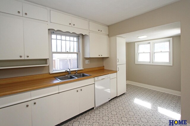 kitchen with white cabinets, baseboards, white dishwasher, and a sink