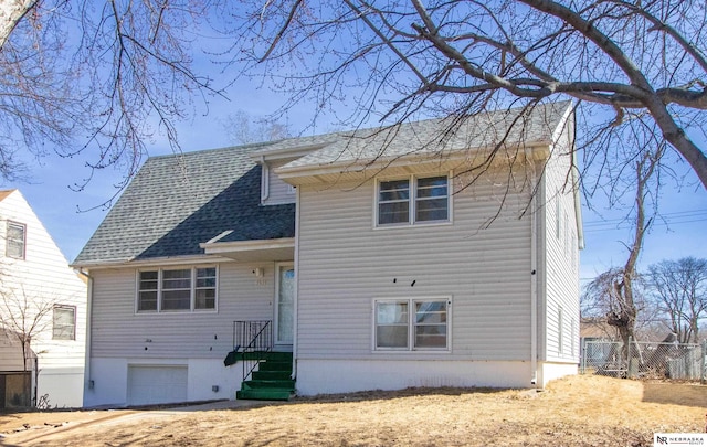 view of front of property featuring an attached garage, roof with shingles, and fence