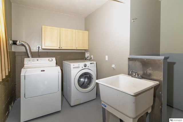 clothes washing area with a sink, cabinet space, and washing machine and clothes dryer