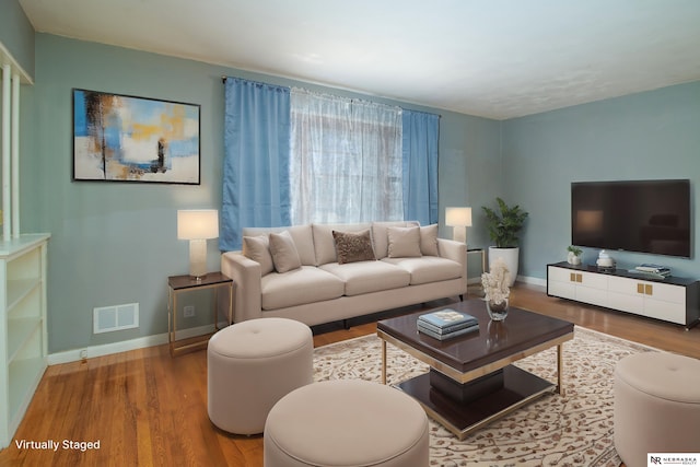 living area featuring visible vents, baseboards, and wood finished floors