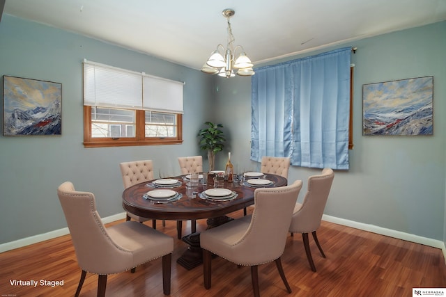 dining space featuring a chandelier, baseboards, and wood finished floors