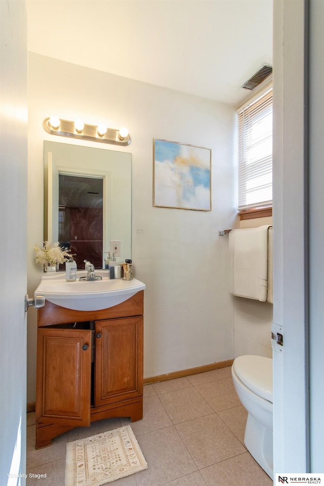 half bathroom featuring tile patterned flooring, visible vents, baseboards, toilet, and vanity