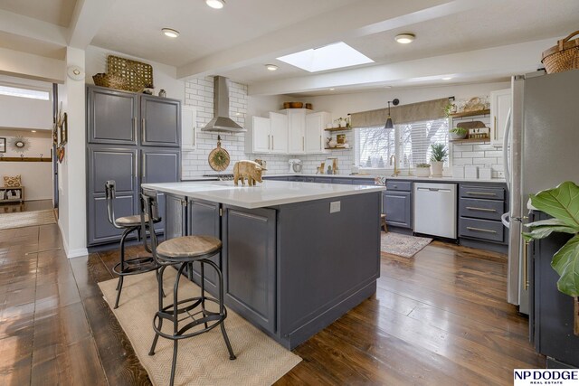 kitchen featuring open shelves, wall chimney range hood, a skylight, and stainless steel appliances