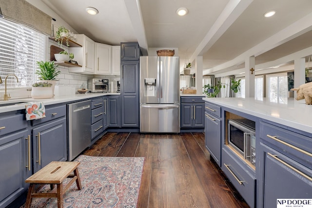 kitchen with dark wood finished floors, decorative backsplash, stainless steel appliances, and light countertops